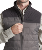 Gray quilted vest with black accents worn by a person on a white background