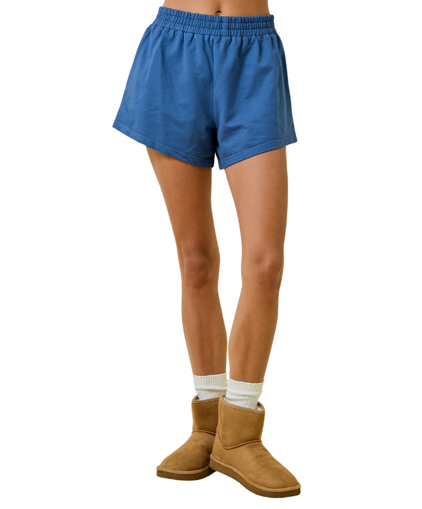 Blue shorts worn by a person with brown boots on a white background