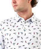 Man wearing a white polo shirt with a duck and shotgun shell pattern of small images and buttons.