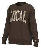 A dark brown crewneck sweatshirt featuring the word 'LOCAL' printed across the chest in large varsity-style letters filled with a camouflage pattern. The sweatshirt is shown on a clean white background.