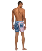 Man wearing American flag patterned swim shorts on a white background