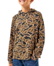 A child wearing a long-sleeve hooded shirt with an allover camouflage-style pattern in tan, brown, and black, paired with blue jeans against a plain white background.