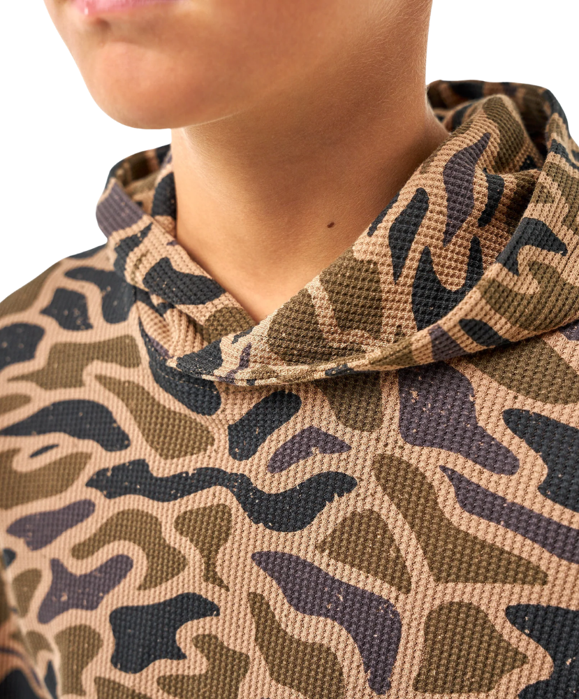 Close-up of a person wearing a textured hooded sweatshirt with a camouflage pattern in tan, olive green, and dark charcoal gray.