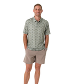 Man wearing a green flying duck patterned polo shirt and beige shorts on a white background