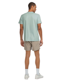 Man wearing a light green t-shirt and beige shorts on a white background