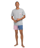 Man wearing a gray t-shirt and American flag shorts on a white background
