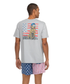 Person wearing a gray t-shirt with a graphic design and American flag shorts on a white background
