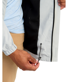 Close-up of a person adjusting the zipper on a white jacket with black trim.