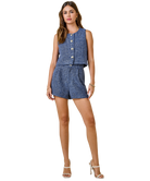 Woman wearing a blue patterned sleeveless top and shorts set on a white background