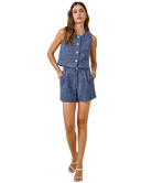 Woman wearing a blue patterned sleeveless top and shorts on a white background