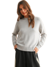 Woman wearing a light gray sweater and black skirt on a white background