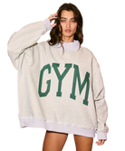 Woman wearing a beige sweatshirt with 'GYM' printed in green on a white background