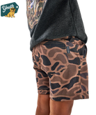 Camouflage shorts worn by a person with a brand logo in the corner.