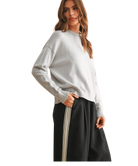 Woman wearing a light gray sweater and black pants with a white background