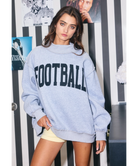 Woman wearing a heather grey sweatshirt with 'FOOTBALL' printed on it against a white background