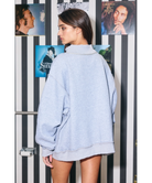 Woman wearing a heather grey sweatshirt with 'FOOTBALL' printed on it against a white background