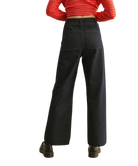 Person wearing black wide-leg pants with a red and white striped shirt on a white background