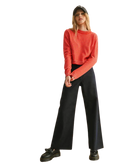 Person wearing a red striped sweater and black pants on a white background