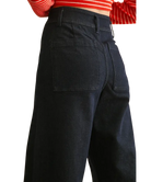 Black pants worn with a red and white striped top on a white background