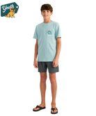 KID wearing a light blue HUK t-shirt with a bass design on the back, standing against a white background.