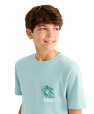 Young boy wearing a light blue HUK t-shirt with a graphic design of a bass on a white background