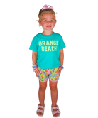 Young girl wearing a turquoise 'Orange Beach' shirt and colorful shorts on a white background