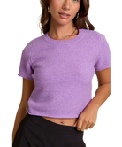 Woman wearing a purple knit top against a white background