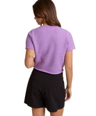 Person wearing a purple top and black shorts on a white background