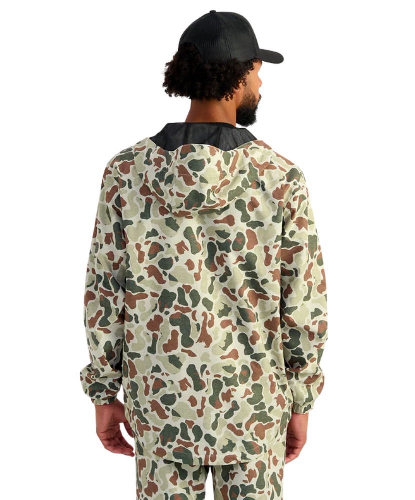 Man wearing a camouflage HUK jacket and hat on a white background