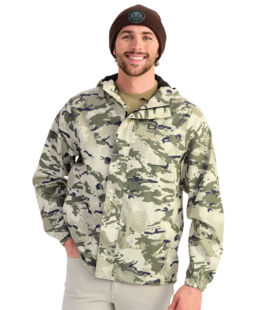 Man wearing a camouflage HUK jacket and beanie on a white background