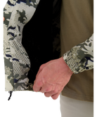 Close-up of a person wearing a HUK jacket with patterned sleeves and a brown body.