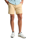 Person wearing beige shorts and white sneakers on a white background