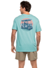Man wearing a light blue t-shirt with a graphic design on the back, standing against a white background.