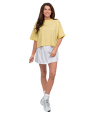 Woman wearing a yellow top and white skirt on a white background