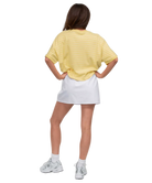 Person wearing a yellow oversized shirt and white skirt on a white background