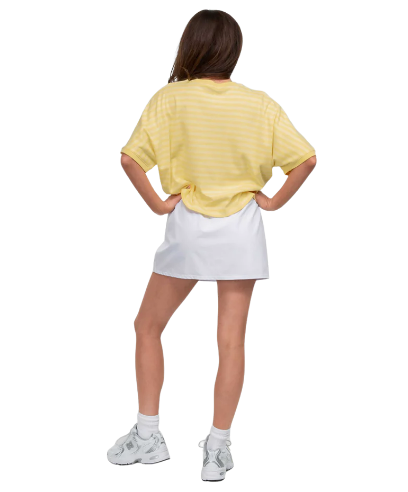 Person wearing a yellow oversized shirt and white skirt on a white background