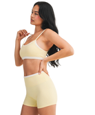 Woman wearing a yellow sports bra and shorts set on a white background