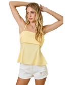 Woman wearing a yellow top and white shorts on a white background