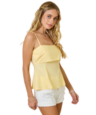 Woman wearing a yellow top and white shorts on a white background