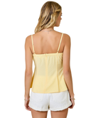 Woman wearing a yellow top and white shorts on a white background
