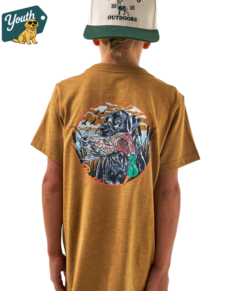 Person wearing a Light brown t-shirt with a colorful lab holding a duck graphic on the back, standing against a white background.