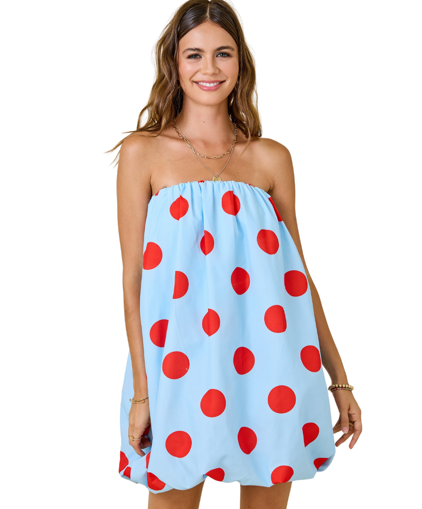Woman wearing a light blue dress with red polka dots on a white background