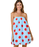 Woman wearing a light blue dress with red polka dots on a white background