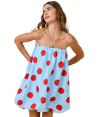 Woman wearing a light blue dress with red polka dots on a white background