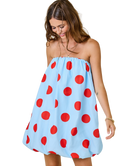 Woman wearing a strapless dress with red polka dots on a white background