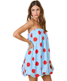 Woman wearing a light blue strapless dress with red polka dots on a white background