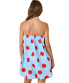Woman wearing a strapless dress with red polka dots on a white background