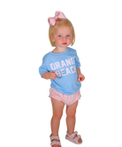 Child wearing a blue 'Orange Beach' shirt and pink shorts on a white background