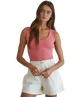 Woman wearing a pink tank top and white shorts on a white background