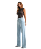 Woman wearring light denim pants with a high rise and wide leg